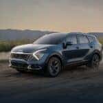 A blue 2024 Kia Sportage driving off-road on dirt