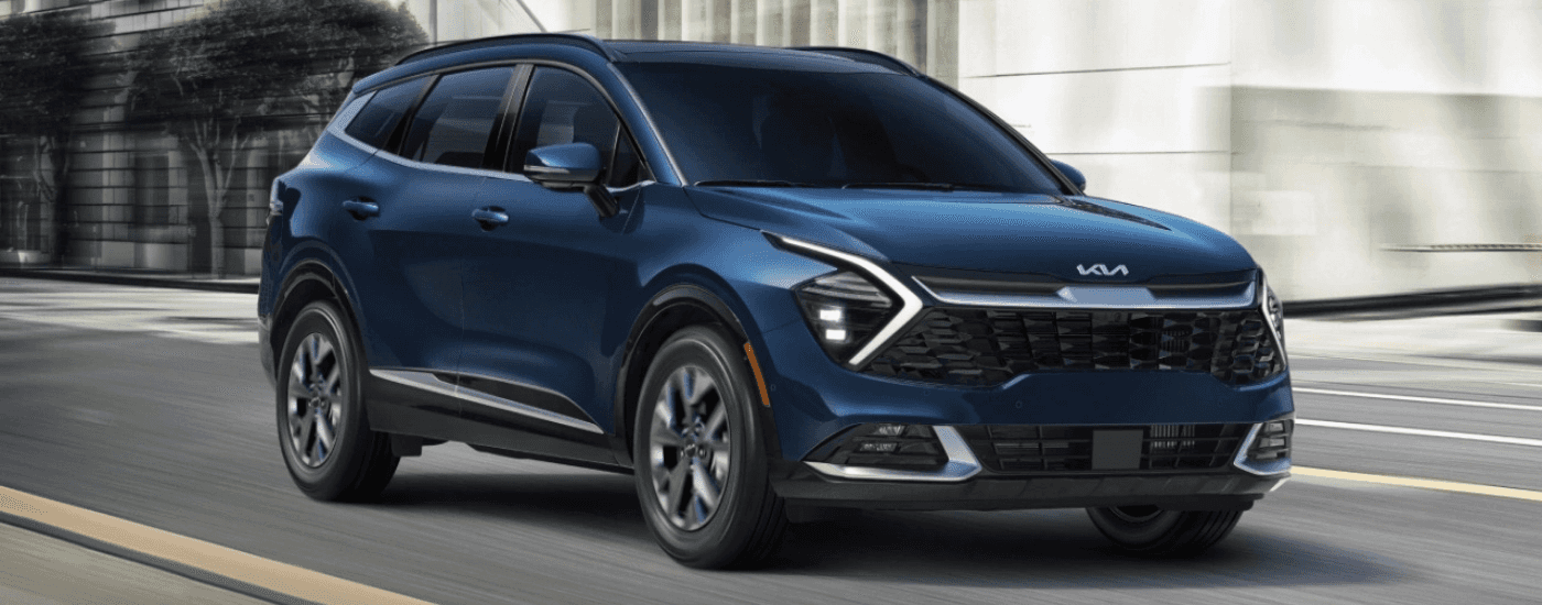 A dark blue 2025 Kia Sportage HEV driving on a city street.