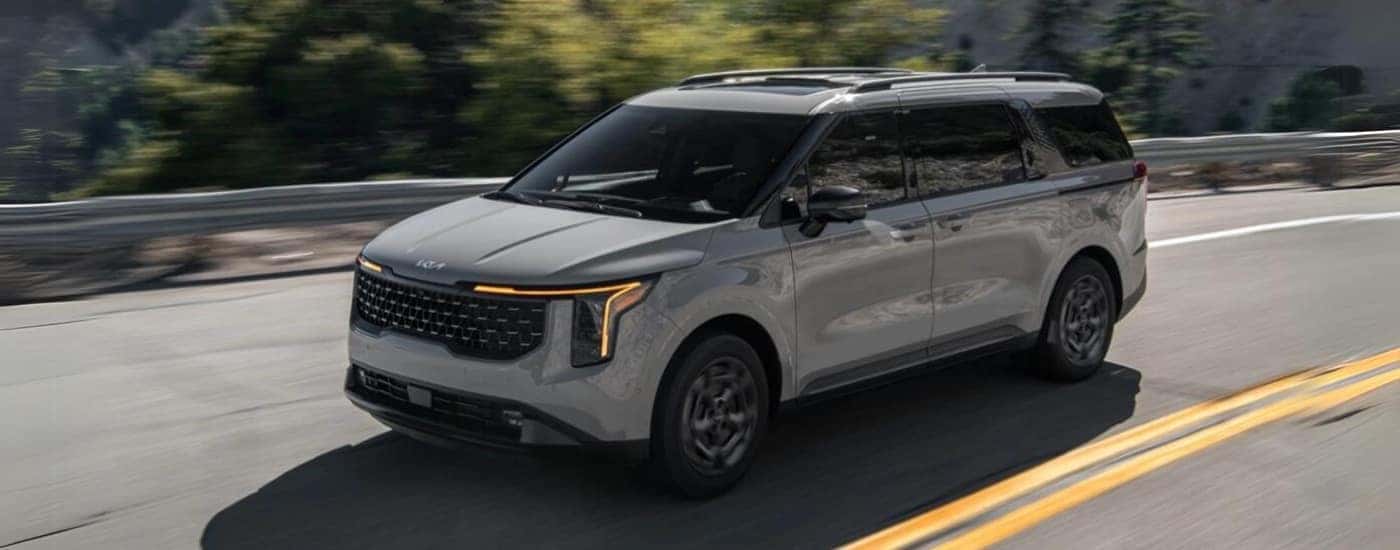 A gray 2025 Kia Carnival is shown driving to a Kia dealer in Knoxville.