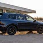 A black 2025 Kia Telluride X-Pro parked near a house.