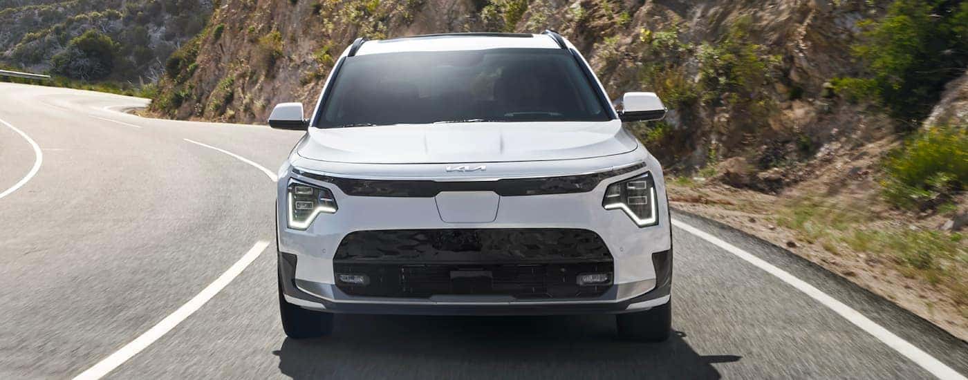 Front of a white 2023 Kia Niro EV driving down an open road.