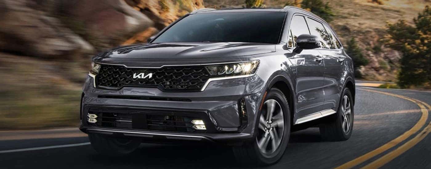 Grey 2024 Kia Sorento Hybrid driving around a bend.