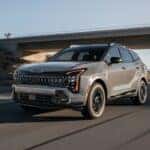 A gray 2026 Kia Sportage driving near an overpass.