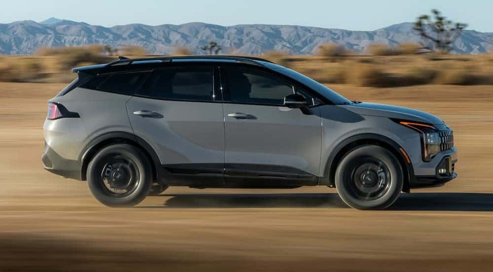 A gray 2026 Kia Sportage X-Pro is driving fast off-road.