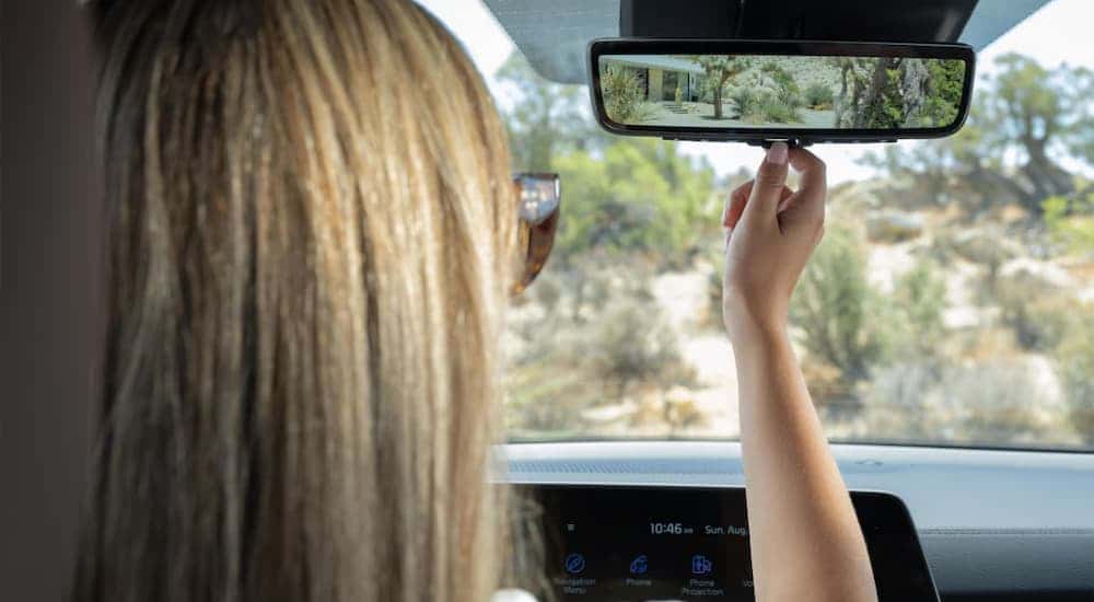 A woman using the rearview mirror in a 2025 Kia Telluride