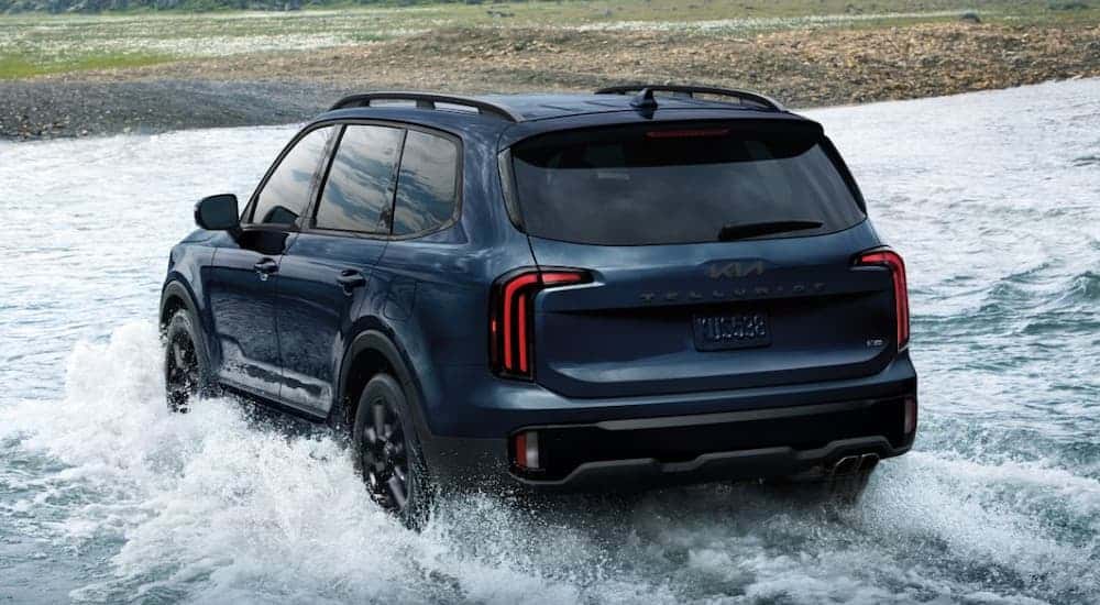 Rear of a black 2025 Kia Telluride fording a shallow river.