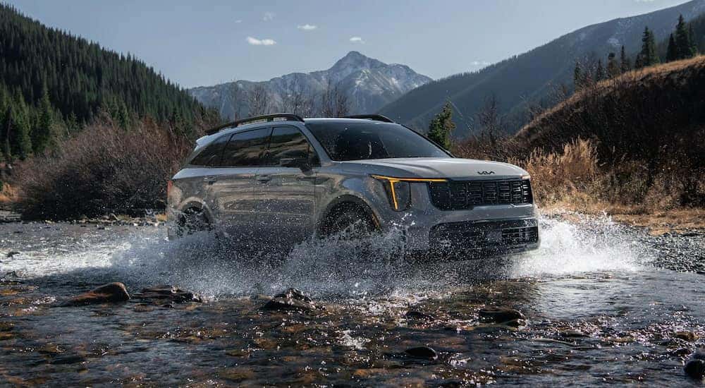 Green 2026 Kia Sorento driving through a creek.