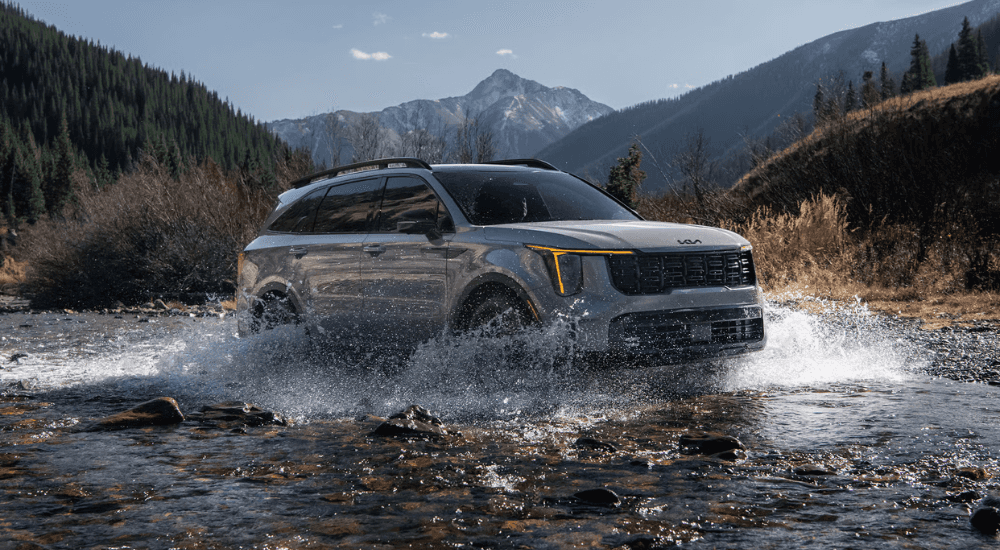 Grey 2026 Kia Sorento driving through a creek