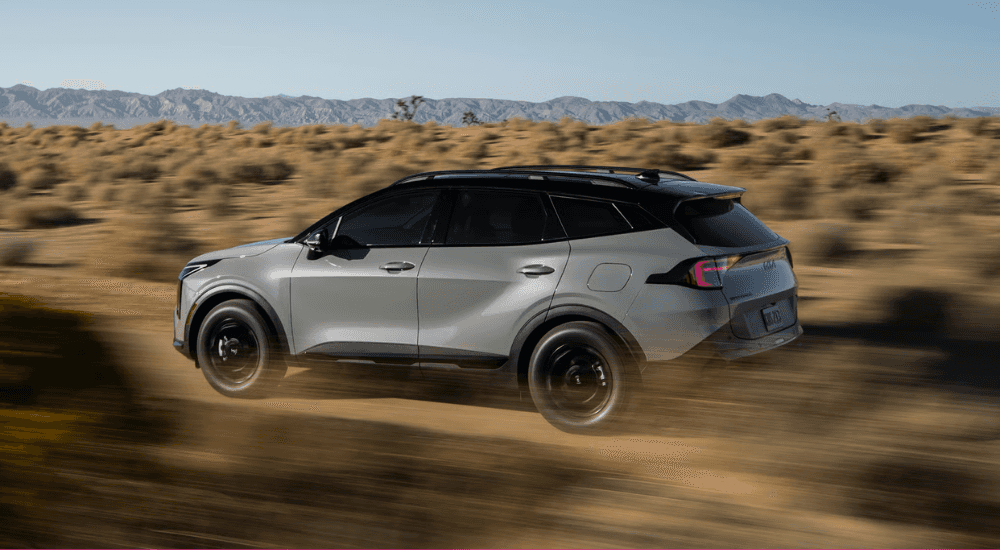 Silver 2026 Kia Sportage driving down a trail