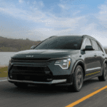 Green 2025 Kia Niro driving on an empty road