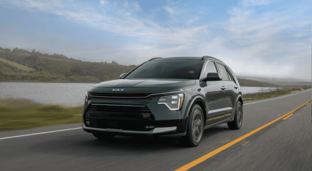 Green 2025 Kia Niro driving on an empty road