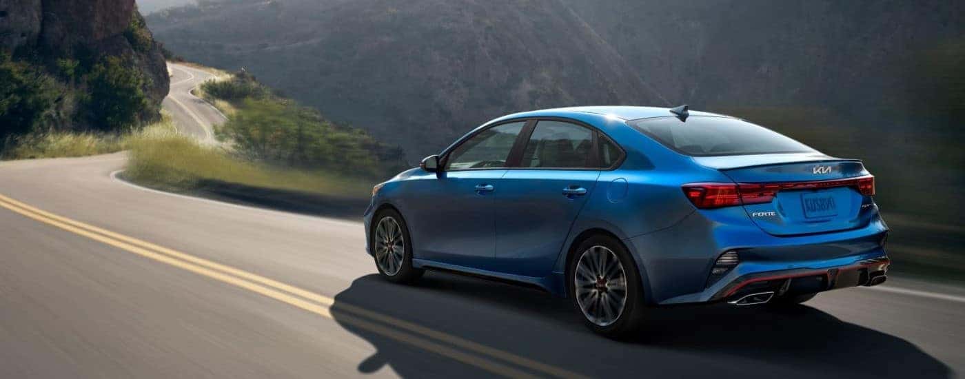 Blue 2023 Kia Forte GT driving through mountains