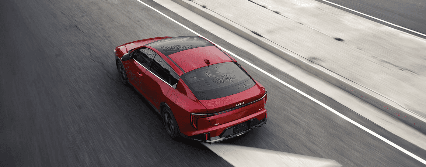 Red 2026 Kia K4 driving down an empty street