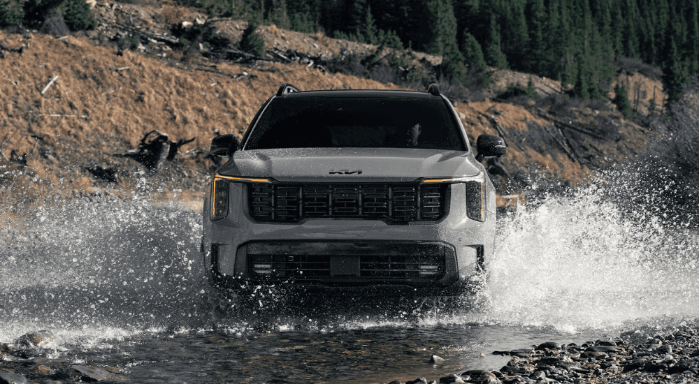 Grey 2026 Kia Sorento driving through a creek