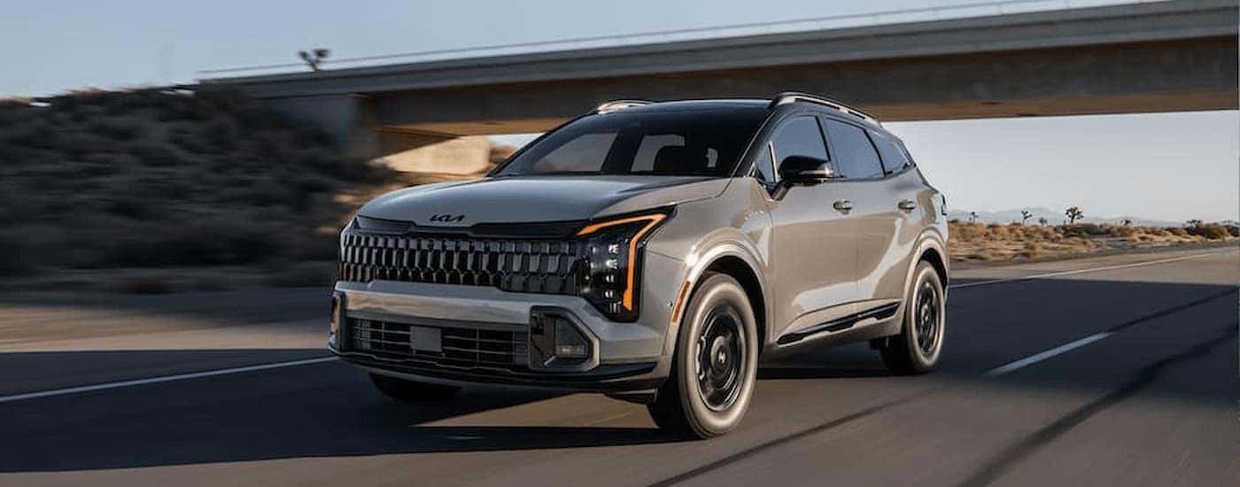 A tan 2026 Kia Sportage driving on a highway
