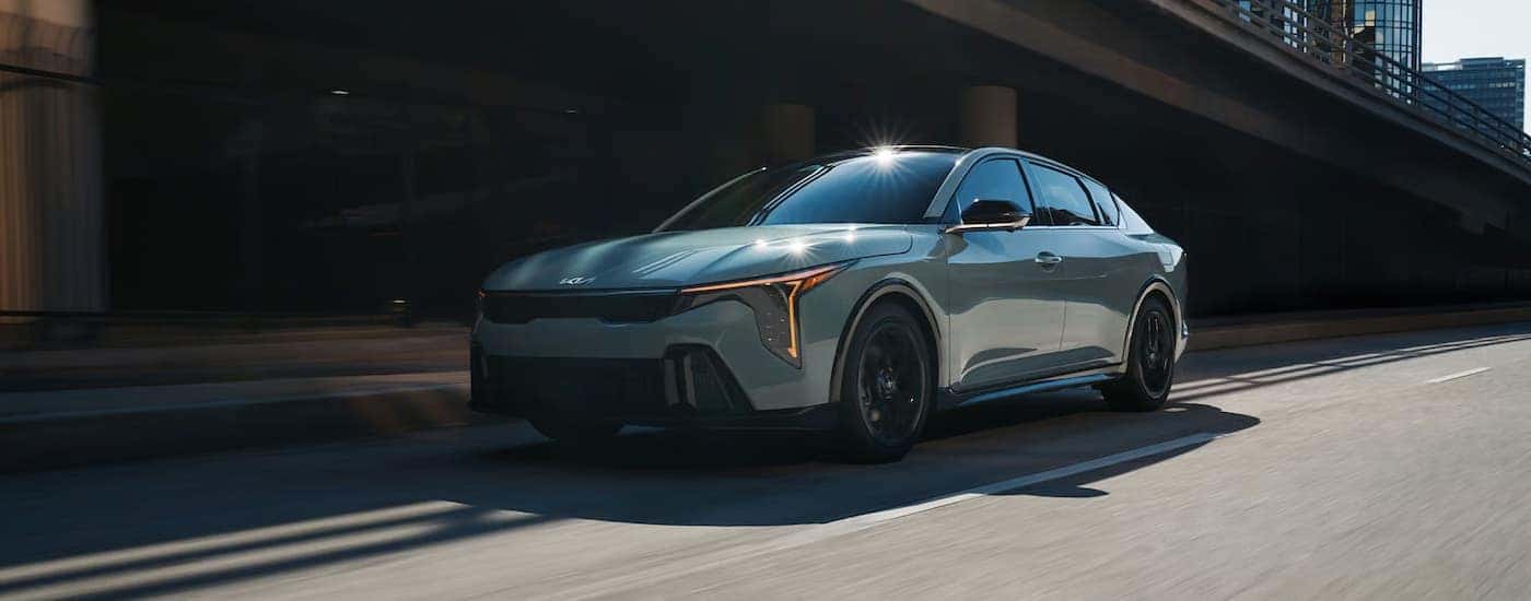 A silver Kia K4 driving in a city