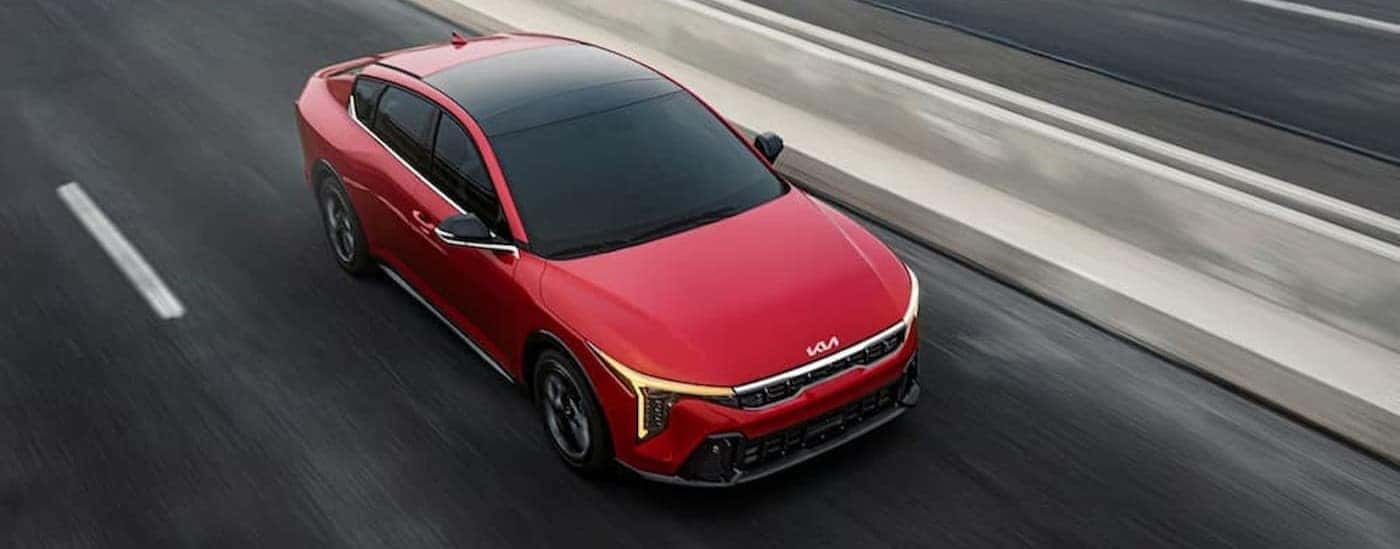 A red 2025 Kia K4 EX driving on a highway to a Kia dealer near Norris.