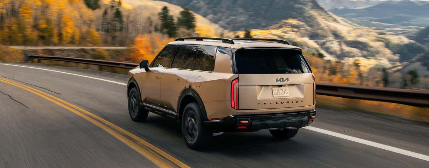 Matte Brown 2027 Kia Telluride X-Pro SX Prestige with Black Exterior badging driving on a road.