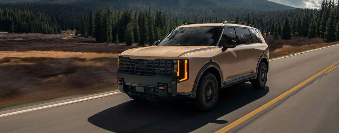Brown 2027 Kia Telluride X-Pro SX Prestige with Black Inner Wheel Arches driving on a road.