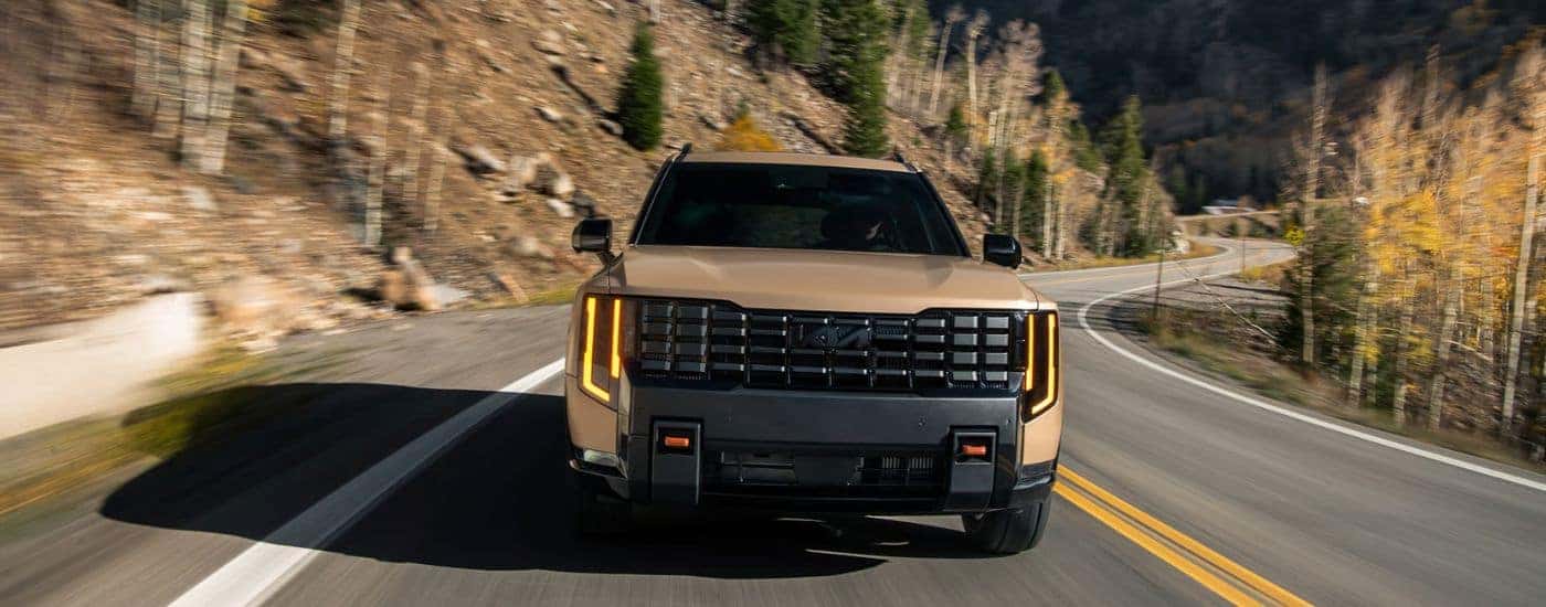 Brown 2027 Kia Telluride X-Pro SX Prestige from the front driving down a windy road.