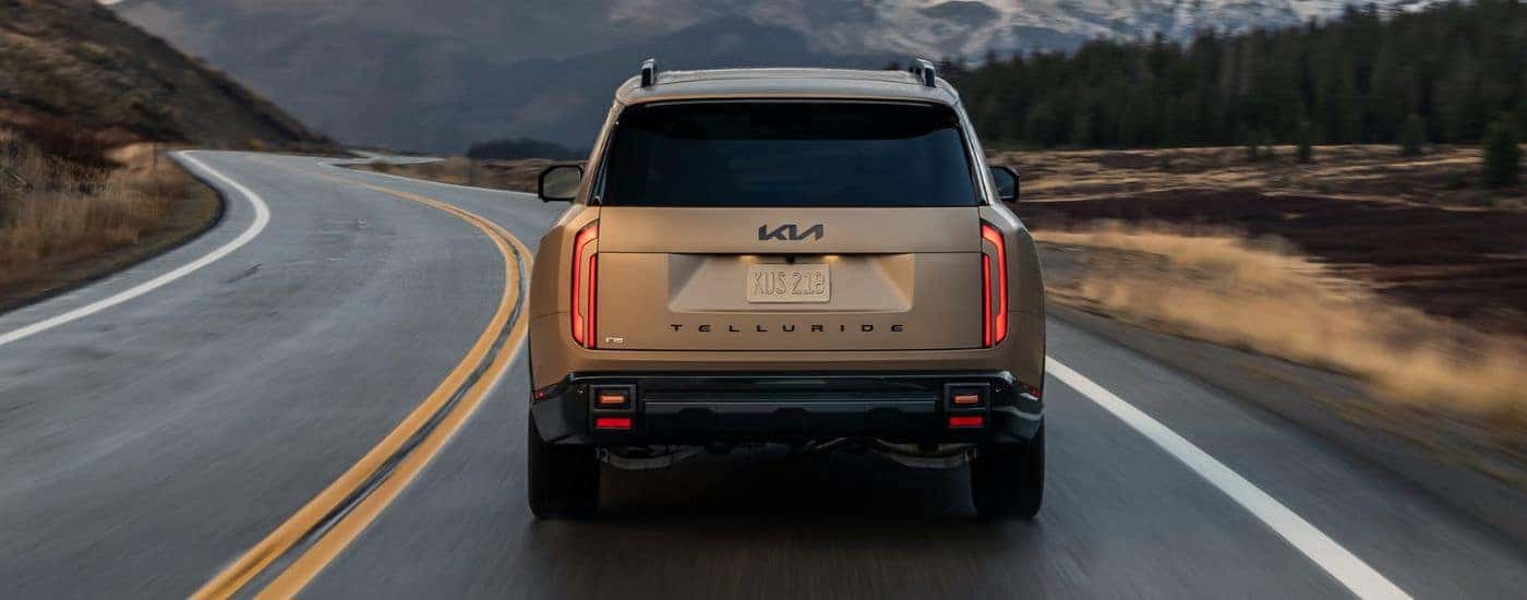 Rear view of a Matte Brown 2027 Kia Telluride X-Pro SX Prestige while driving down the road.