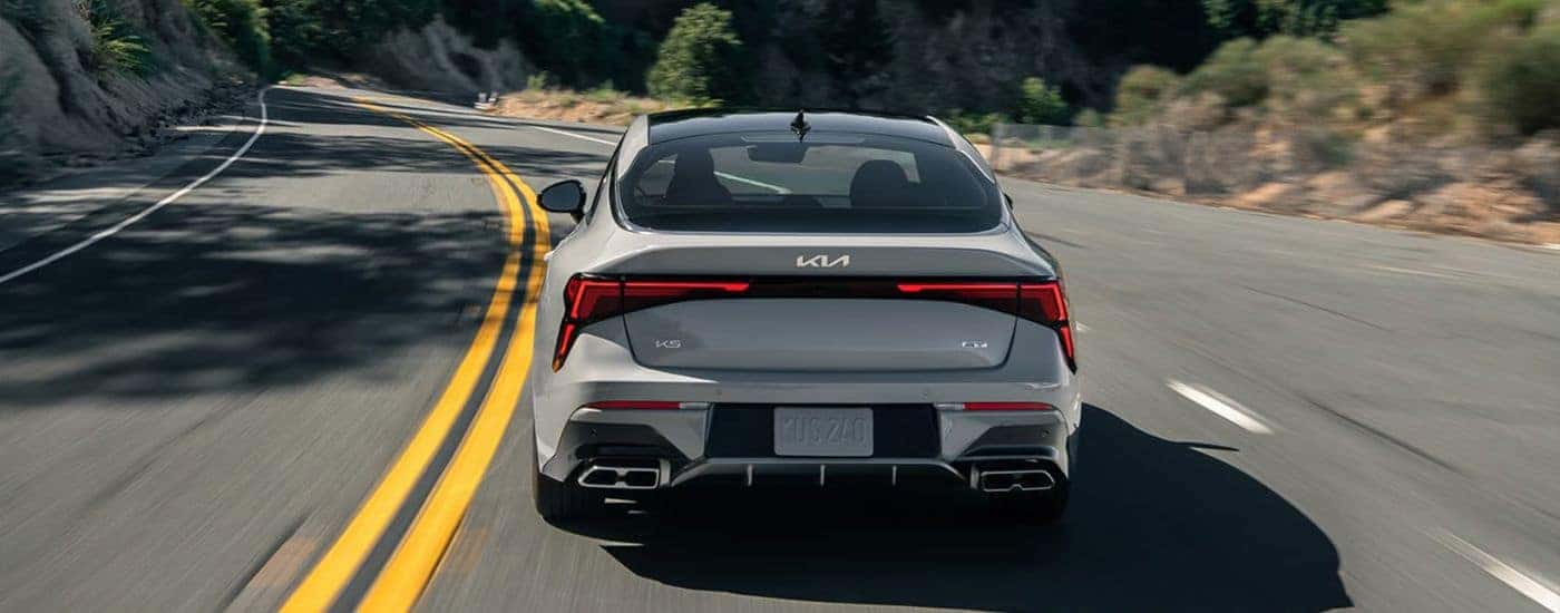 Grey 2026 Kia K5 GT rear view on a paved road.