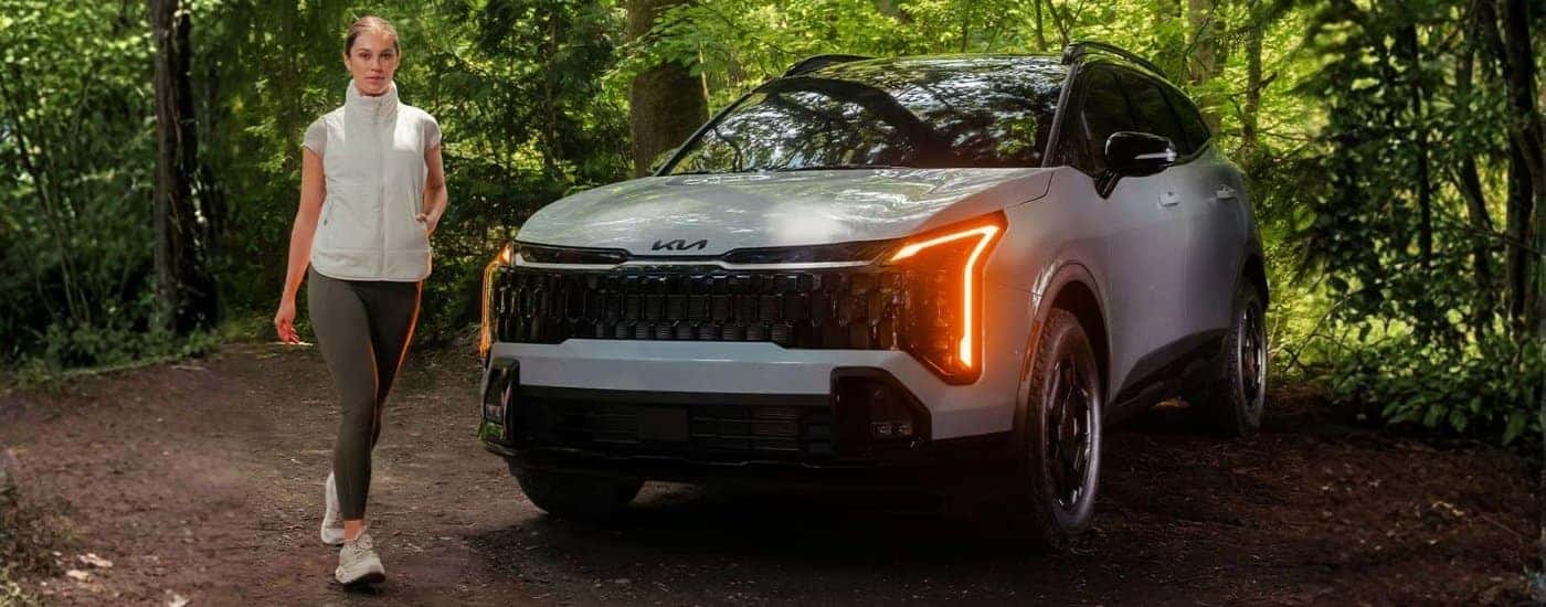 Person walking near a white 2026 Kia Sportage for sale near Harriman