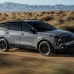 A gray 2026 Kia Sportage X-Pro Prestige driving a dirt road.