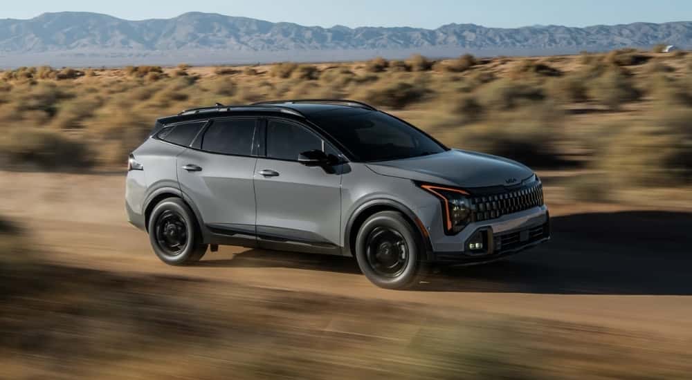 A gray 2026 Kia Sportage X-Pro Prestige driving a dirt road.