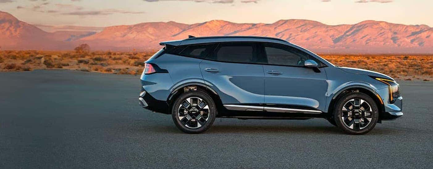 A blue 2026 Kia Sportage parked near a mountain.