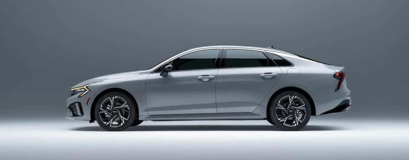 A silver 2026 Kia K5 parked i a gray room/