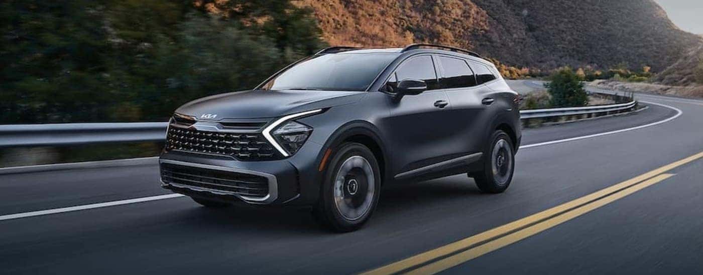 A silver 2023 Kia Sportage driving on a highway.