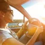 Young woman driving car and speeding on highway in summer