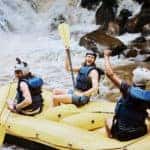 cheerful group of men white water rafting on the river