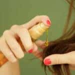 Woman applying hair care product to her hair