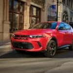A red Hot Tamale Dodge Hornet driving down city streets