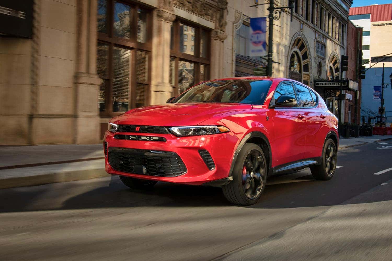 A red Hot Tamale Dodge Hornet driving down city streets