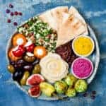Meze platter with green falafel, pita, sun dried tomatoes, pumpkin and beet hummus, olives, stuffed peppers, tabbouleh, figs. Mediterranean appetizer party idea