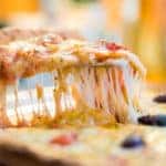 Pizza slice with stretchy cheese being picked up for serving