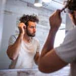 Man looking in the mirror trying to decide how to fix his hair