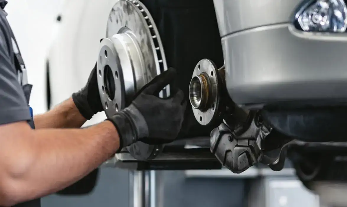 hands removing a tire from a car on a lift 