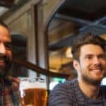 people, leisure, friendship and and bachelor party concept - happy male friends drinking beer at bar or pub