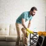 Young man cleaning with a duster