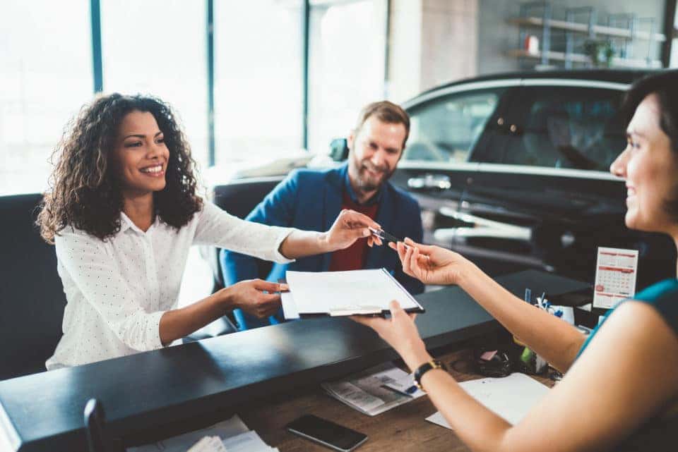 Young woman with her partner signing contract for buying a car