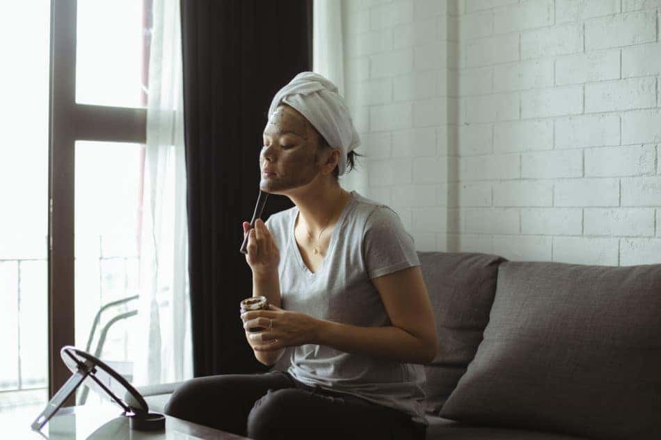 Woman applying a facial on her couch 