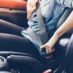 Asian woman fastening seat belt in the car