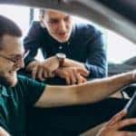 a man sits in the driver seat of a car in a dealership