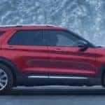 a red explorer, seen from the side, driving on a wintery road