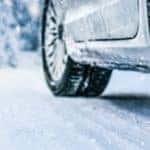 a silver car drives over a snowy road with thickly treaded tires